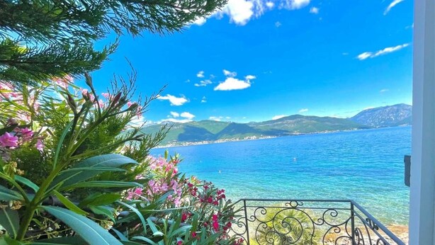 Un balcon offrant une vue dégagée sur la mer et les montagnes.