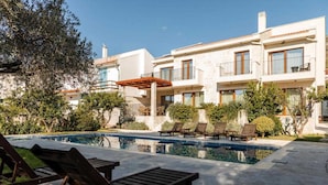 Ein modernes Gebäude mit Swimmingpool, Liegestühlen und einer Pergola.