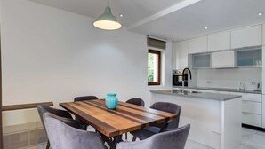 Eine moderne Küche mit weißen Schränken, einem eingebauten Backofen und einer großen Kochinsel mit Spüle.
