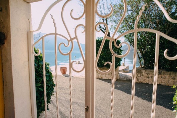 A wrought iron gate leading to a patio with a view of the sea.