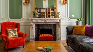 A room with a fireplace, a red armchair, a black sofa, and a wooden coffee table. - The Old Beech (Antwerp)