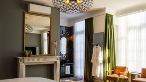 A hotel room with a large bed, a fireplace, a bathroom with a bathtub, and a view of the city. - The Old Beech (Antwerp)