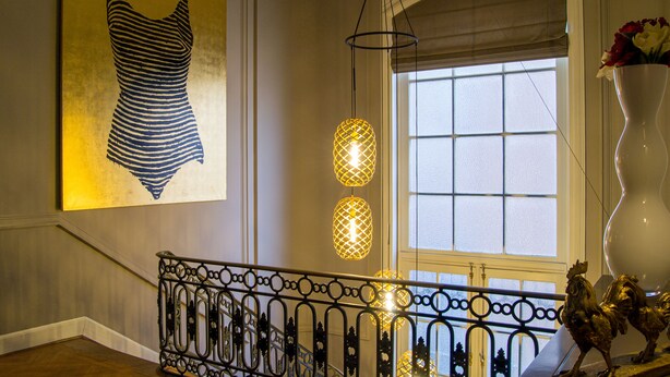 A grand interior with a large framed artwork, ornate metal railing, and a decorative vase with flowers. - The Old Beech (Antwerp)