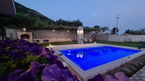 A swimming pool with a stone wall and a staircase leading up to a terrace. - Villa Charming Vineyard (Budva)