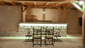 Una habitación rústica con paredes de piedra, techo de madera y una zona de bar central.