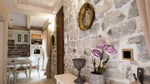 A rustic stone wall with a vintage mirror, a decorative bowl, and a vase with flowers. - Villa Stella Adriatica (Tivat)