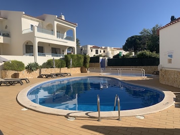 Pool area with sun beds, umbrellas and children’s pool.