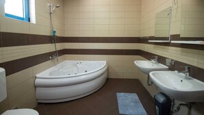 Un baño con bañera, dos lavamanos y una ventana.