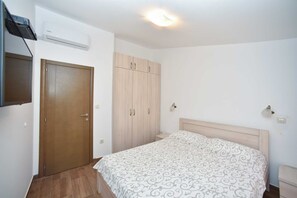 Ein Schlafzimmer mit Holzschrank, Bett mit gemustertem Überwurf und montiertem Fernseher.