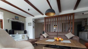 Een moderne woonkamer met een houten salontafel, een beige bank en een televisie op de achtergrond.