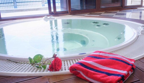 A hot tub with a rose and a striped towel on a wooden deck.