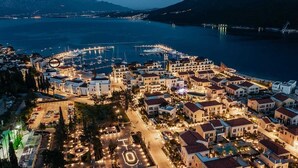 Une ville côtière dotée d’un port de plaisance, de bâtiments aux toits rouges et bordée d’une vaste étendue d’eau.