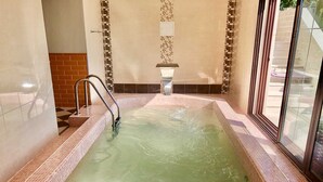 Un jacuzzi con borde de azulejos y escalera de metal.