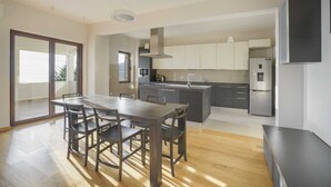 Una cocina moderna con una isla central, un comedor con mesa y sillas, y un ventanal que aporta luz natural.