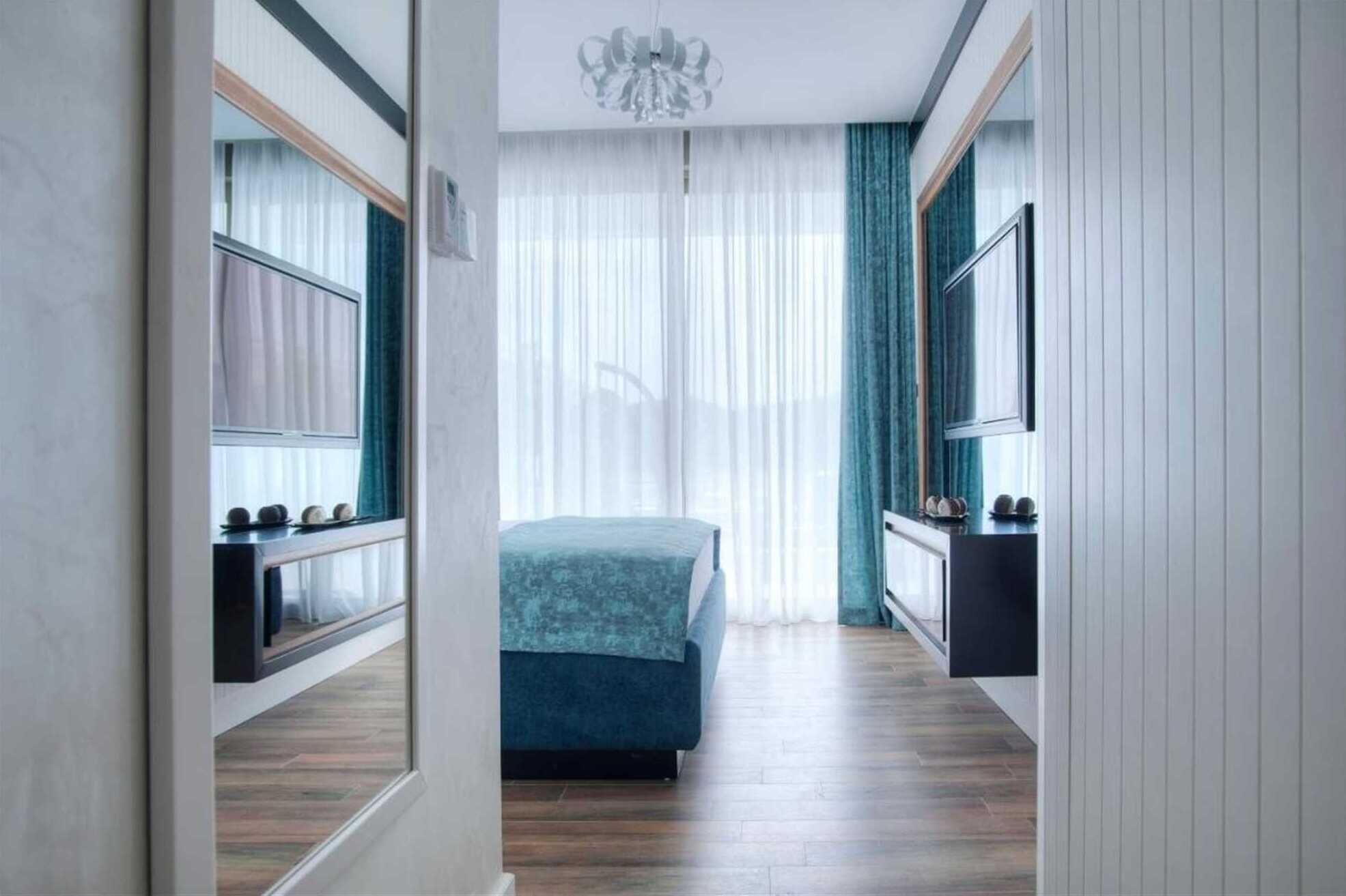 A modern bedroom with a bed, a TV, and a mirror.