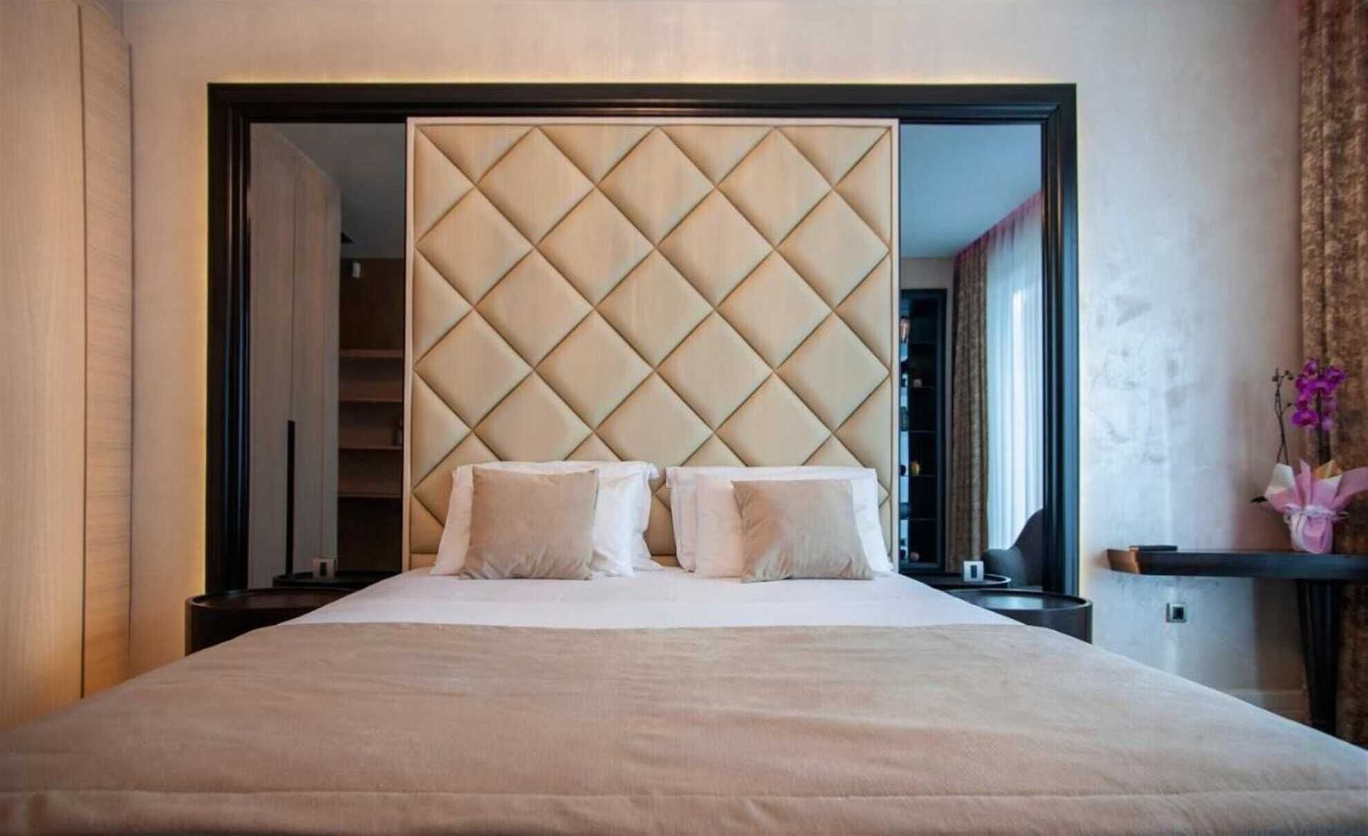 Ein Hotelzimmer mit einem großen Bett, einem gepolsterten Kopfteil und einem Nachttisch.