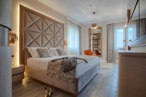 A modern bedroom with a large bed, a built-in headboard, bedside tables, a dresser, a mirror, and a bookshelf.