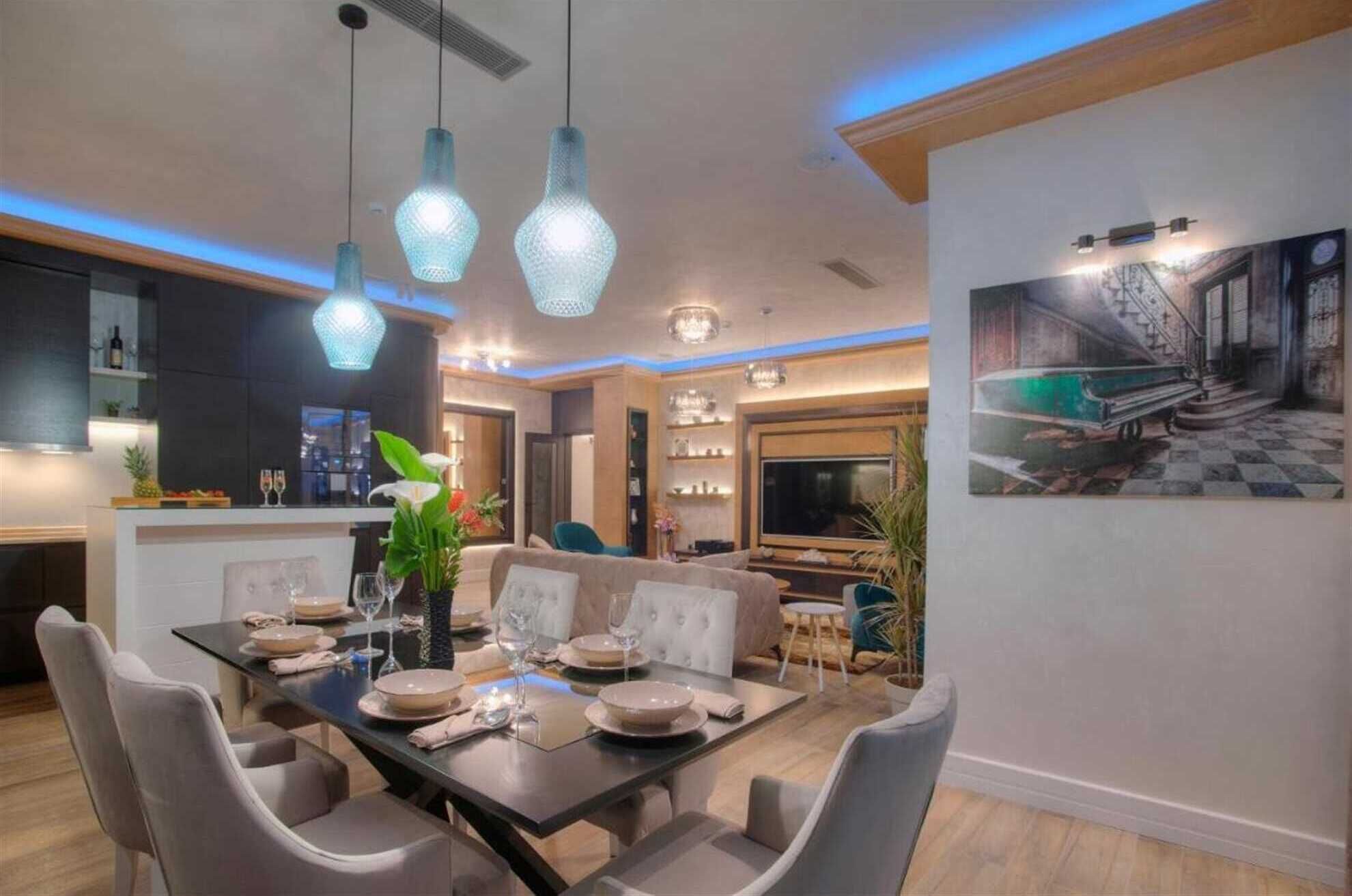 Un espace repas moderne avec une grande table dressée pour six personnes, entourée de chaises grises à revêtement en tissu.