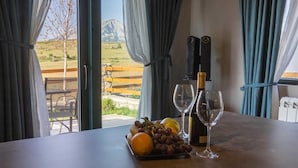 A table with a bottle of wine, two wine glasses, and a plate of fruit. - Authentic Mountainside Villa Lusso (Zabljak)