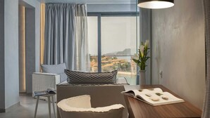 A modern living room with a large window, a dining table, and a cozy seating area.