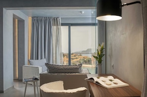 A modern living room with a large window, a dining table, and a cozy seating area. - Villa Geba Appolonia Seaview (Budva)