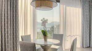 A modern dining area with a round table, four grey upholstered chairs, and a hanging light fixture.
