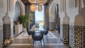 A dining area with a long table, black chairs, and hanging woven light fixtures. - Villa Geba Suite Salma (Budva)