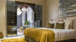 A bedroom with a bed, a sofa, a coffee table, and a decorative archway. - Villa Geba Suite Salma (Budva)