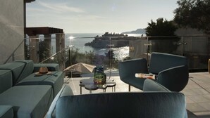 A modern outdoor seating area with a view of the sea and a cityscape. - Villa Geba Suite Salma (Budva)