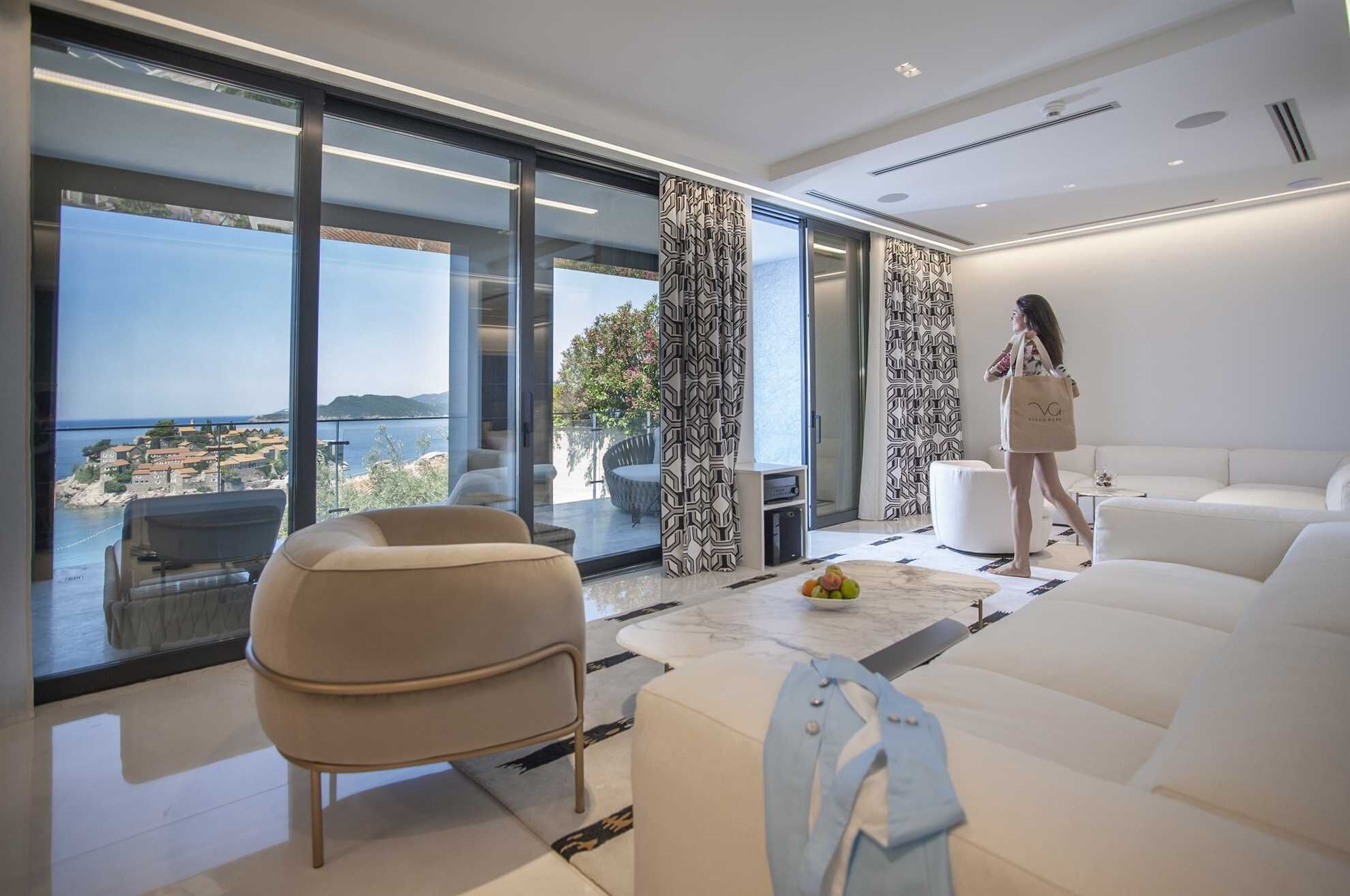 A modern living room with a large glass door leading to a balcony with a scenic view.