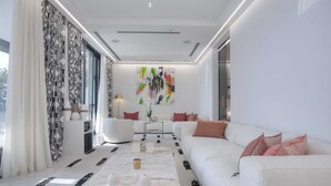 Un moderno salón con un sofá blanco, una mesa de centro y un cuadro abstracto y colorido en la pared.