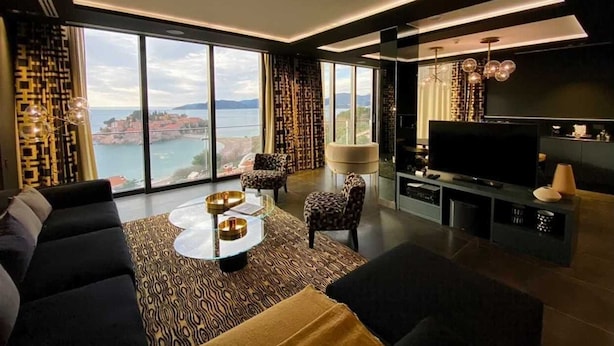 A modern living room with a large TV, comfortable seating, and a view of the sea. - Villa Geba Suite Elena (Budva)