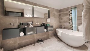 Une salle de bain moderne avec un grand miroir, une baignoire sur pieds et un meuble-lavabo doté d’un porte-serviettes.