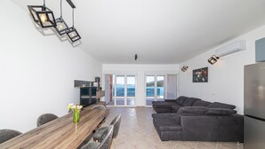 A modern living space with a wooden dining table, dark grey sofa, and a kitchen area with a refrigerator. - Beautiful apartment in Marina (Marina)