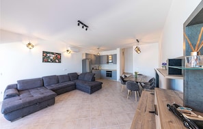 A modern living room with a sectional sofa, a dining area with a wooden table and chairs, and a kitchen in the background. - Beautiful apartment in Marina (Marina)