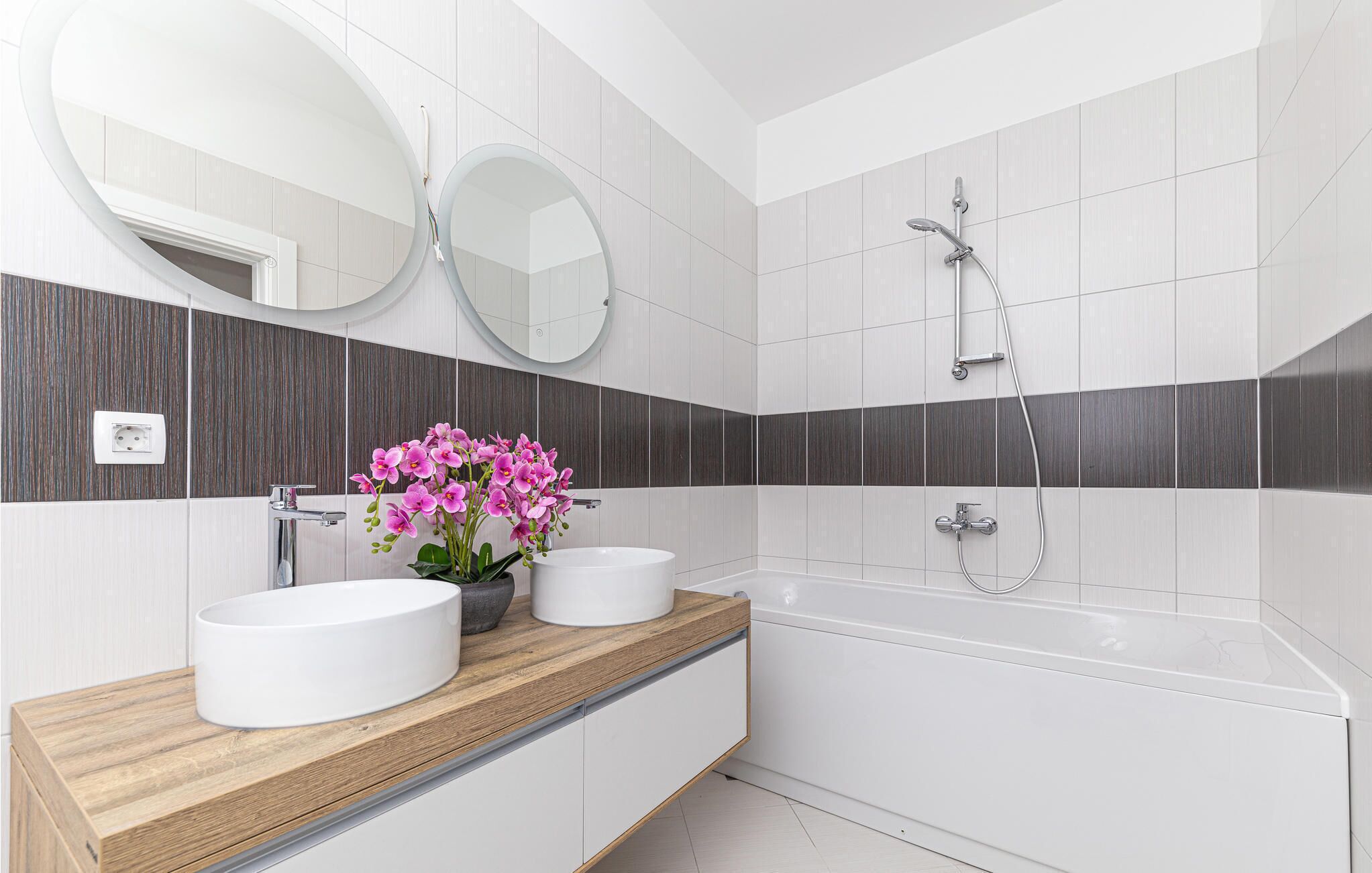 A modern bathroom with two sinks, a bathtub, and a shower.