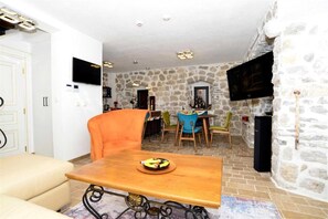 A dining area with a wooden table, chairs, and a stone wall.