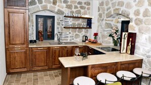 Una cocina con paredes de piedra, armarios de madera, una isla grande con taburetes de bar y un arco de piedra.