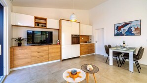 Een moderne keuken met houten kastjes, een inbouwoven en een eethoek met een tafel en stoelen.