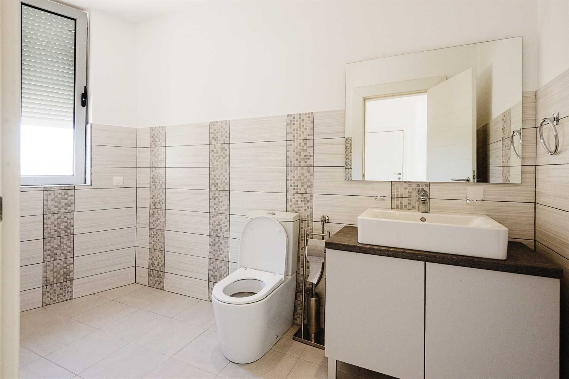 A bathroom with a toilet, sink, and mirror.