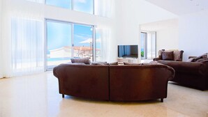 A modern living room with large windows, a flat-screen TV, and a sectional sofa. - Luxury Seaview Villa Krimovica 2 (Budva)