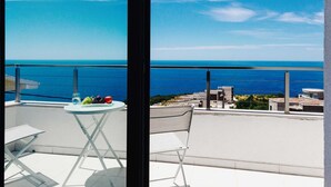 A balcony with a table and chairs, overlooking a coastal view with buildings and a clear sky. - Luxury Seaview Villa Krimovica 2 (Budva)