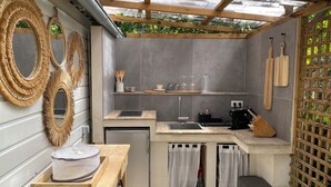 A compact kitchen with a built-in refrigerator, a sink, and a wooden table with a food container. - Mini Villa With Jacuzzi (Cagnes sur mer)