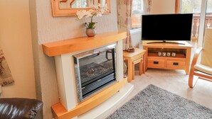 Una sala de estar con chimenea, televisión y techo de madera.