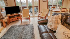 Una sala de estar acogedora con un sofá de cuero, dos sillones mecedores, un televisor de pantalla plana y un comedor con mesa y sillas.