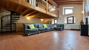 Un'ampia zona giorno con una scala in legno, un divano e un pavimento piastrellato.