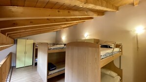 Una stanza piccola e accogliente, in legno, con letti a castello e una scrivania.
