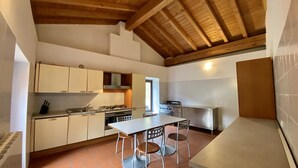 Una cucina con mobili bianchi, un fornello e un'area pranzo con due sedie.