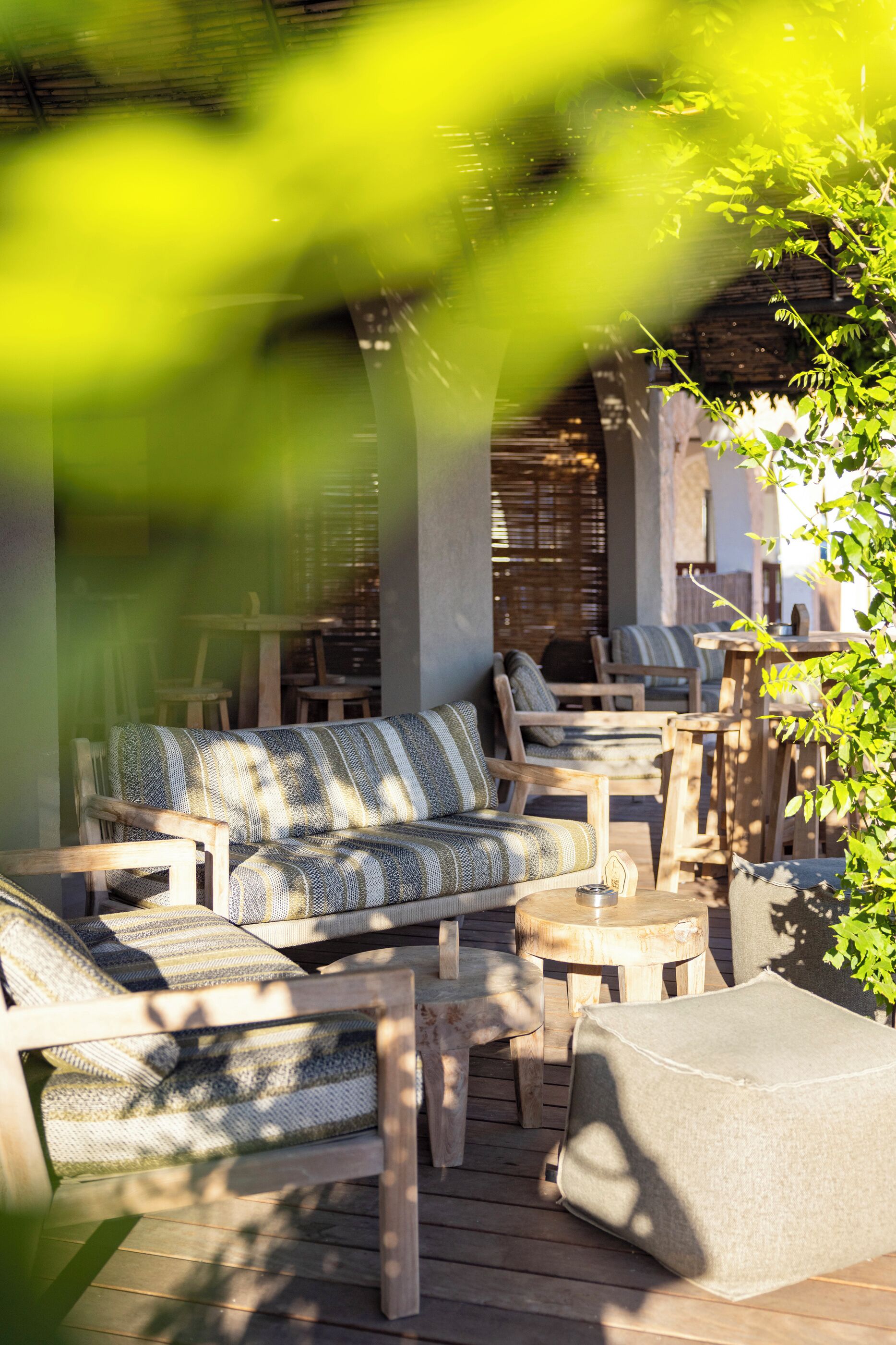 Une terrasse en bois avec un espace salon extérieur comprenant des canapés et des fauteuils, ainsi qu’une petite table.
