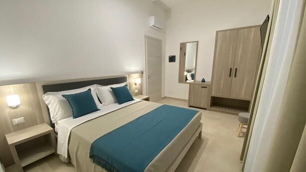 A bedroom with a bed, bedside tables, a wardrobe, and a mirror. - B&B MarAlè (Porto Cesareo)